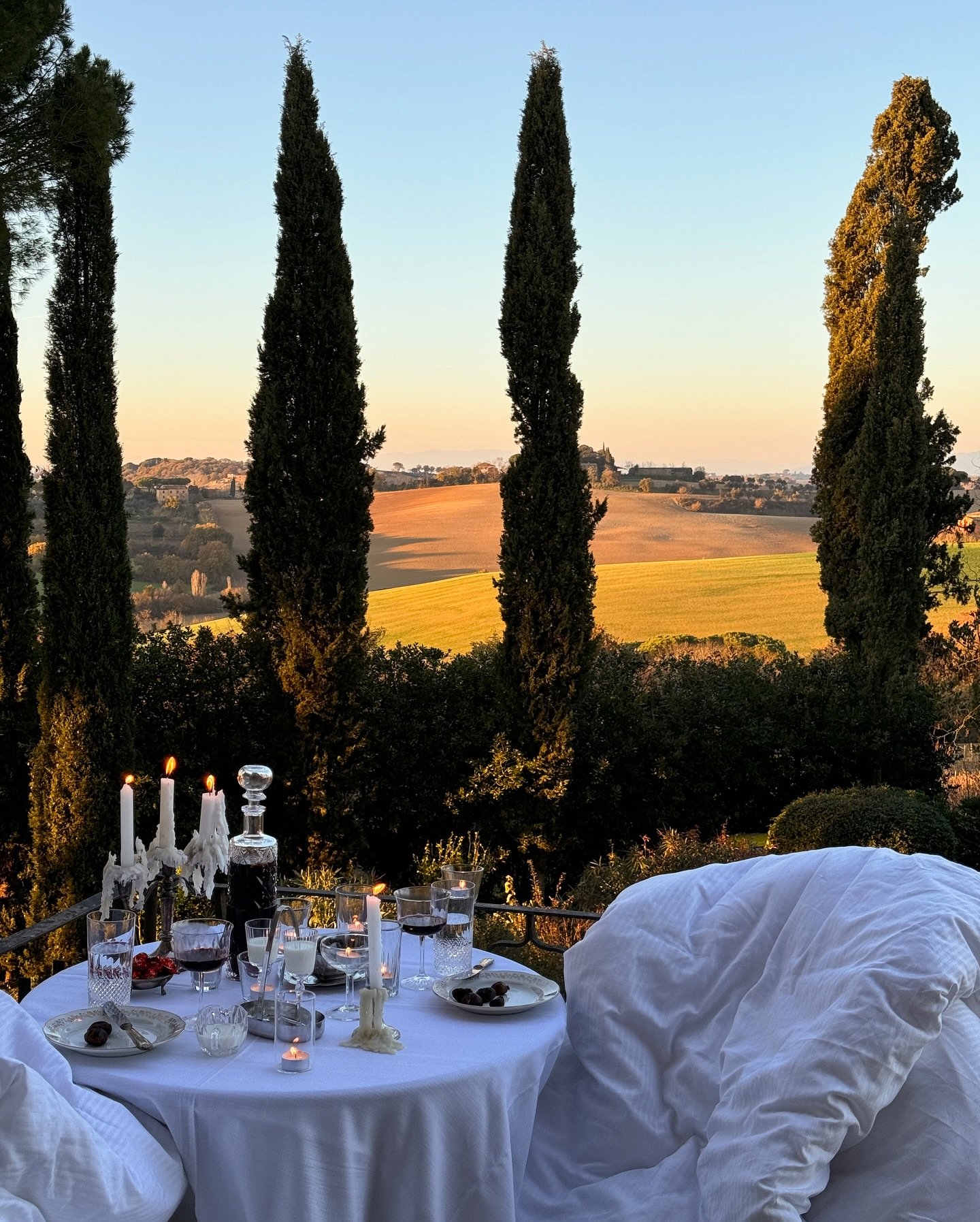 A dinner table above the golden hills of Tuscany at sunset.