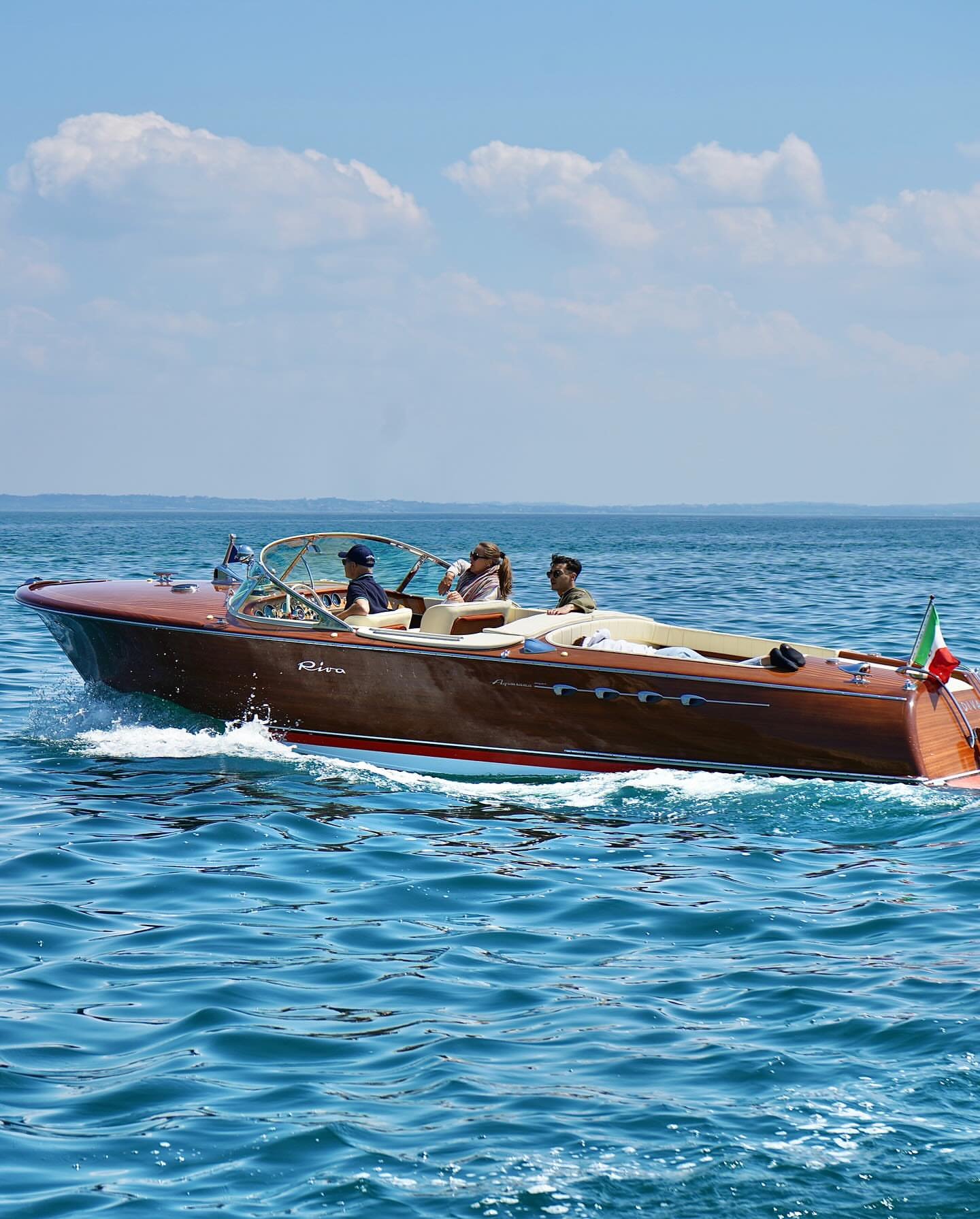 A classic wooden Riva motorboat crossing Lake Como